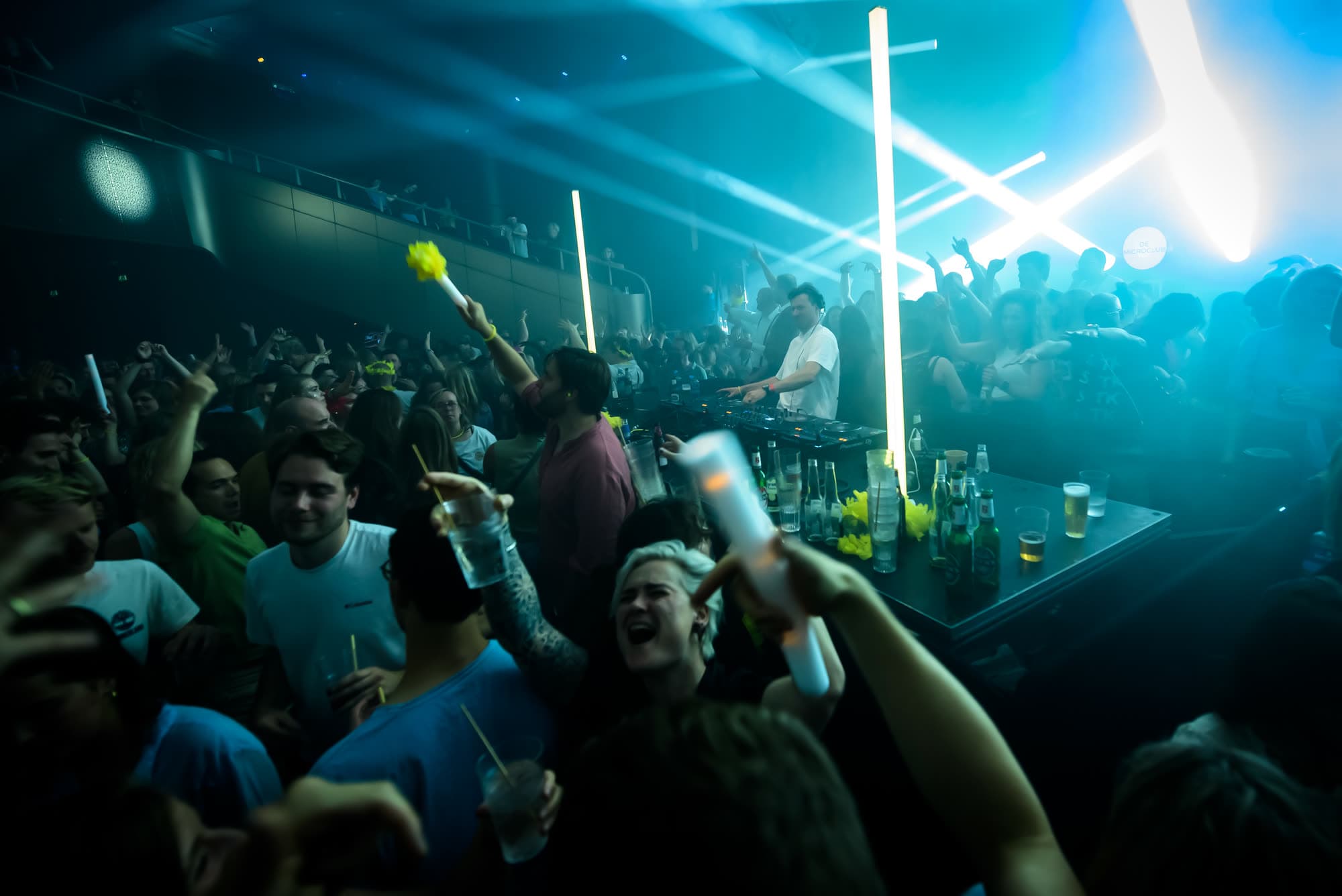 Publiek met glowsticks juicht voor de DJ in blauw licht